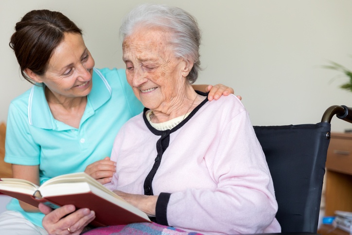 Dementia caregiver and senior adult woman reading a book at Booker T. Washington in Shreveport, LA