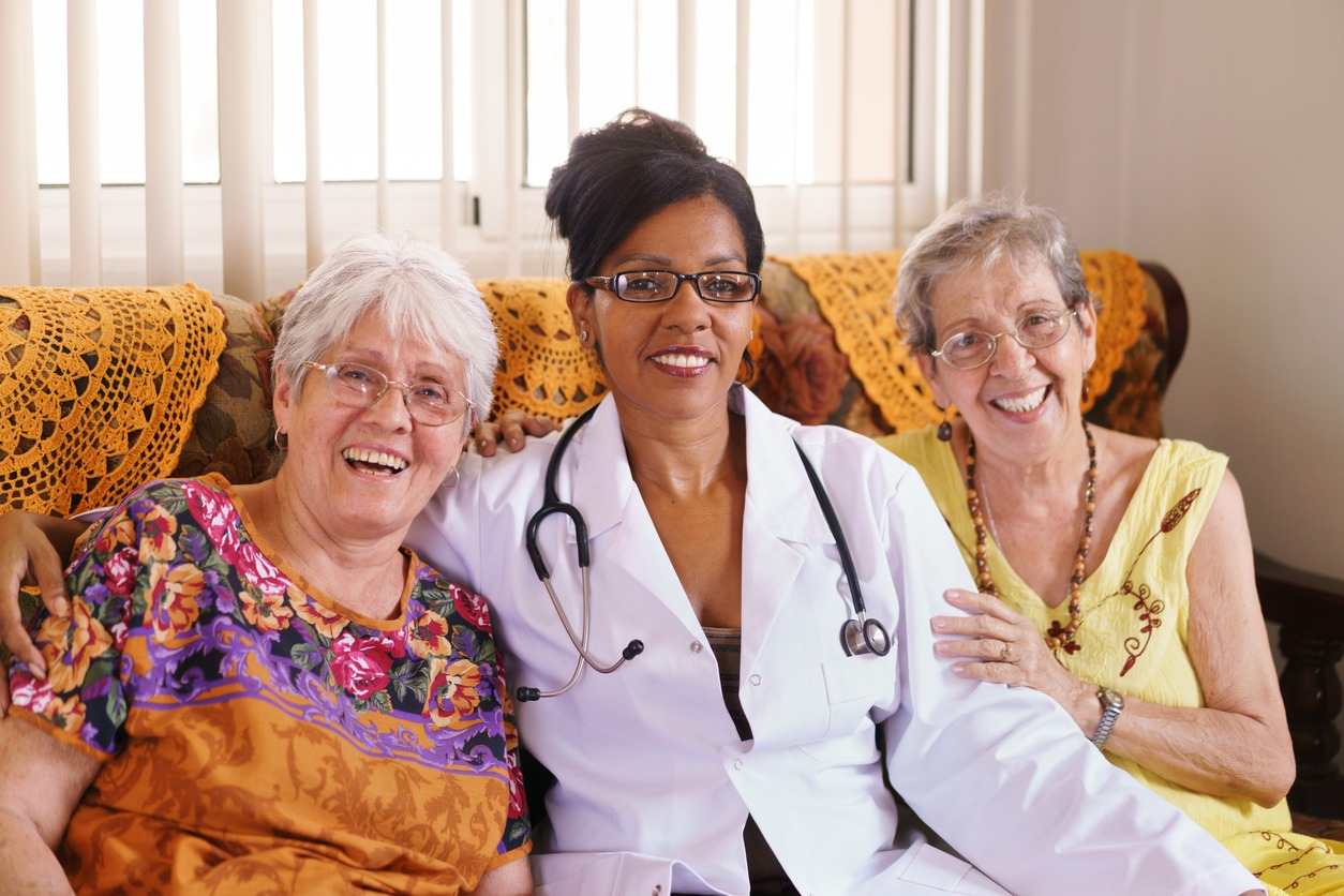 A woman with a stethoscope sits beside two older women, discussing health at Booker T. Washington Skilled Nursing & Rehabilitation in Shreveport, LA