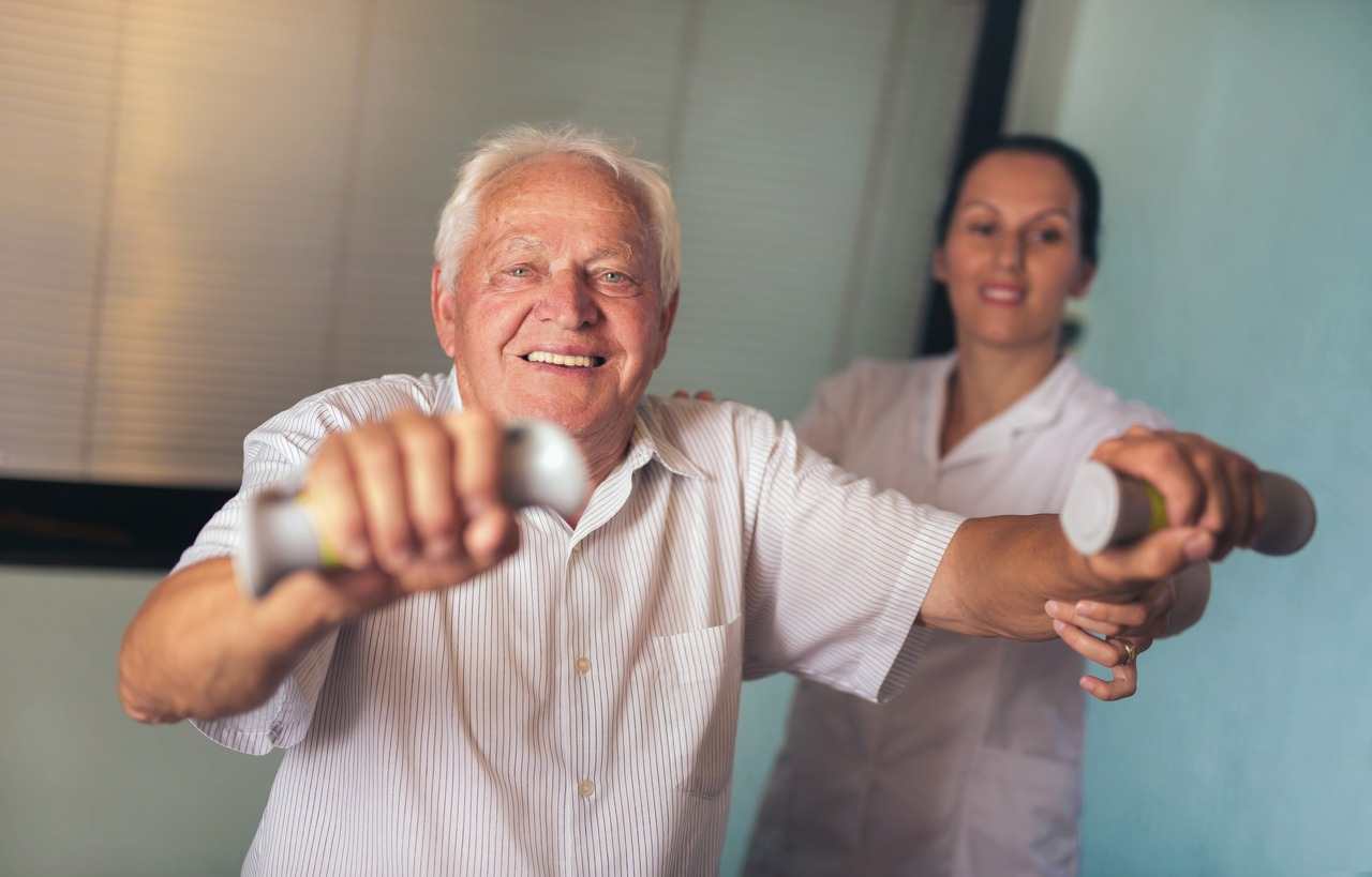 An elderly man and therapist are lifting dumbbells together in outpatient therapy in a skilled nursing facility in Shreveport, LA