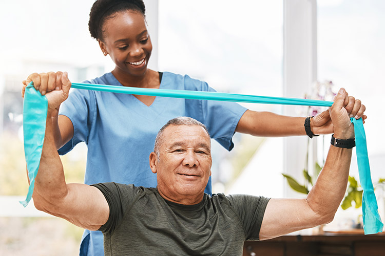 A skilled nursing physical therapist helps a senior man use a resistance band in Shreveport, LA