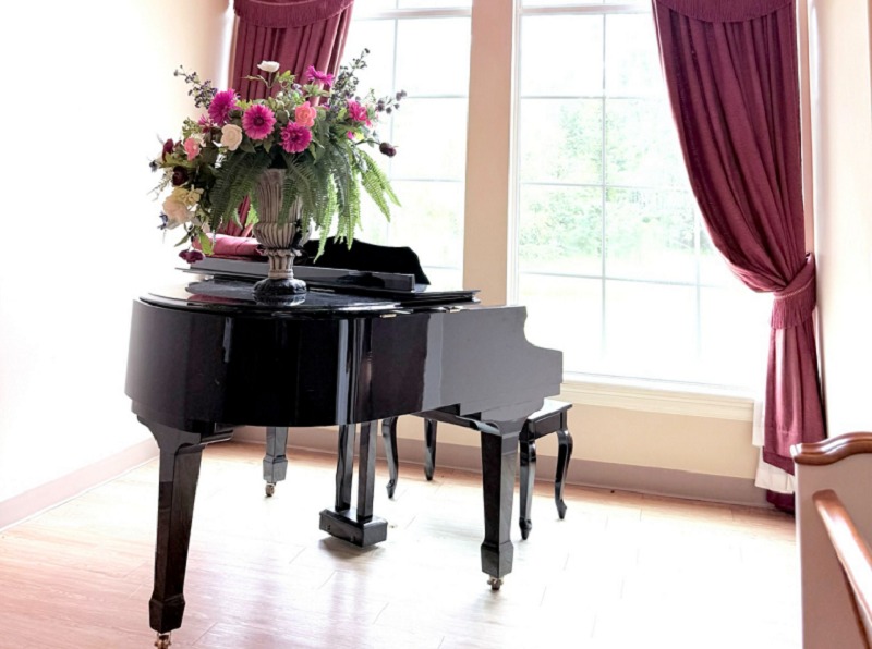 A piano sits by curtained windows where little details make a big difference at Booker T. Washington skilled nursing center in Shreveport, LA