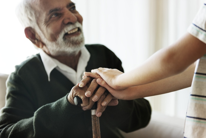 Elderly man and young girl hold hands, symbolizing connection in hospice care, at Booker T. Washington skilled nursing center in Shreveport, LA